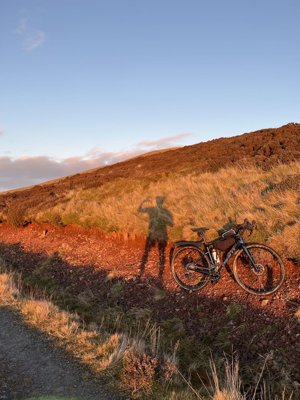 Ahmed taking a picture of his shadow, which is beside his bike, while flexing his biceps within the shadow.